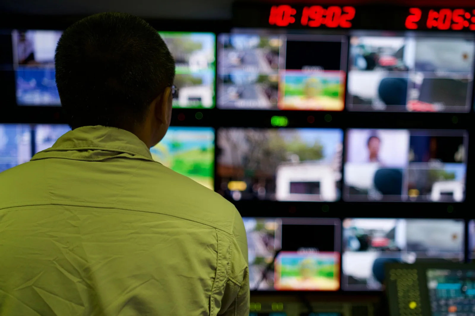 A CCTV operator watching a wall of monitors in a control room