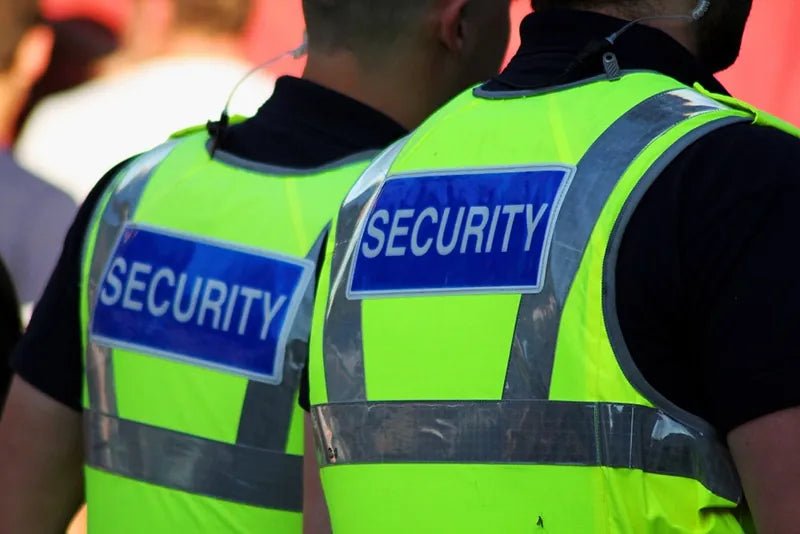 Two security officers in hi-vis SECURITY vests at an event
